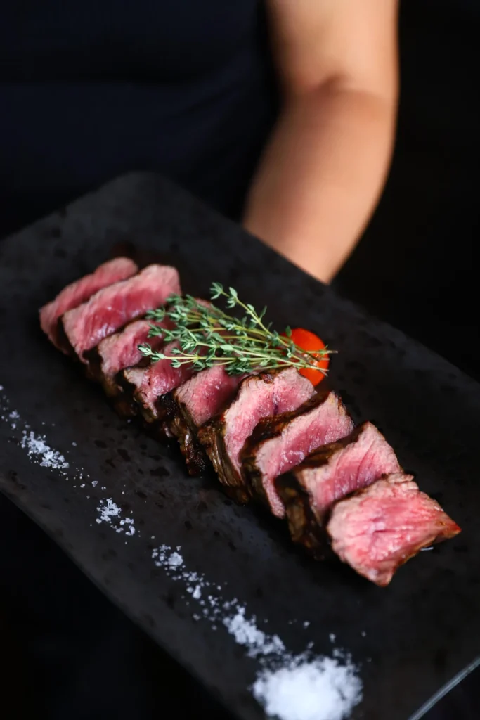 Sliced steak on a dark platter